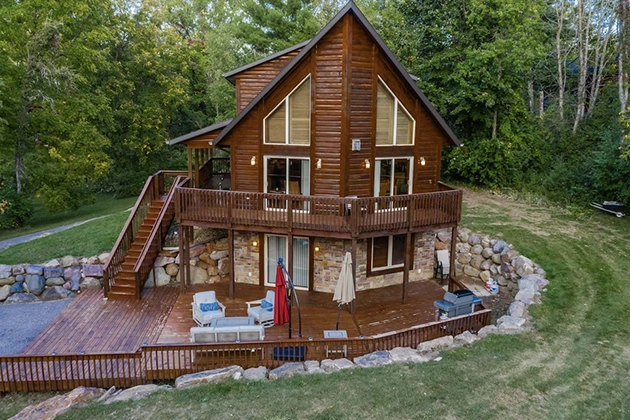 Cozy log home living room with stone fireplace and large front windows